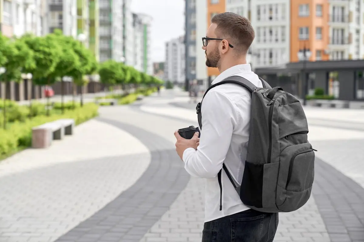 jeune homme marchant sac à dos pour ordinateur dans la ville